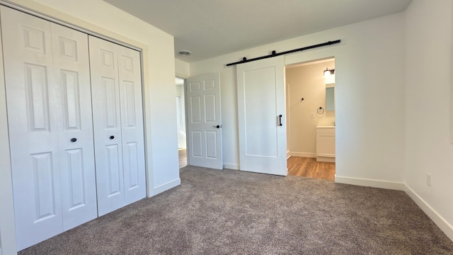 703 2nd St, Henning, MN 56551 - unfurnished bedroom featuring carpet, a closet, a barn door, baseboards, and connected bathroom