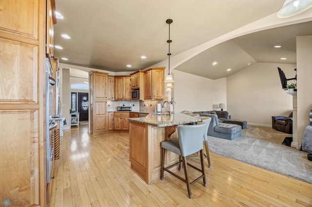 3914 21st Ave S, Moorhead, MN 56560 - kitchen with arched walkways, open floor plan, a kitchen breakfast bar, a peninsula, and light stone counters