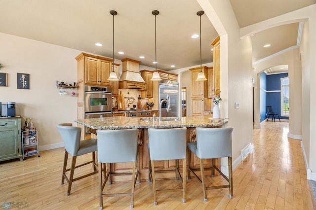3914 21st Ave S, Moorhead, MN 56560 - kitchen featuring appliances with stainless steel finishes, arched walkways, a peninsula, premium range hood, and light stone countertops
