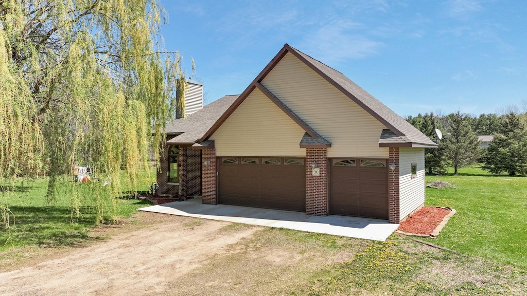 1513 19 1/4 St, Stanley Twp, WI 54822 - view of property exterior featuring brick siding, dirt driveway, a chimney, a yard, and an attached garage