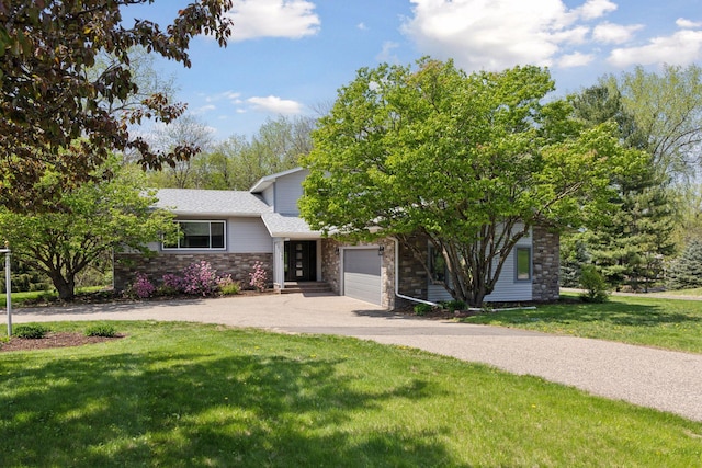 view of front of property with driveway, a front yard, an attached garage, and stone siding