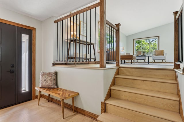 entrance foyer featuring wood finished floors, lofted ceiling, stairway, and baseboards