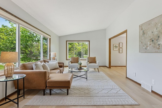 living area with lofted ceiling, light wood-style floors, and baseboards