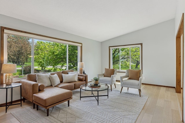 living room with healthy amount of natural light, vaulted ceiling, light wood-style floors, and baseboards