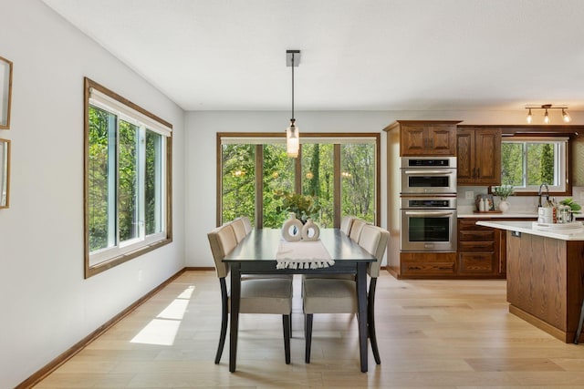 dining room with plenty of natural light, light wood finished floors, and baseboards