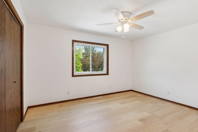 unfurnished bedroom featuring a closet, light wood-style flooring, baseboards, and ceiling fan