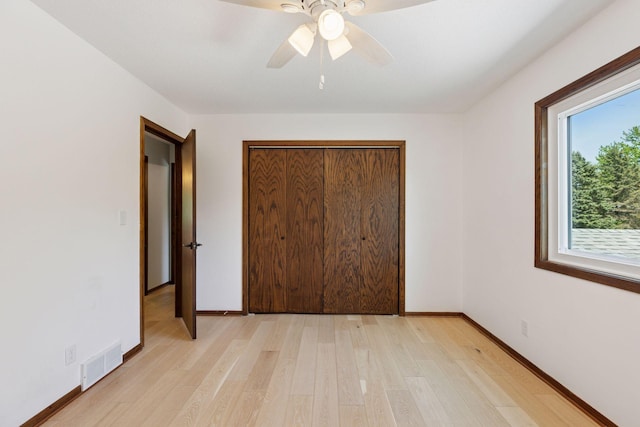 unfurnished bedroom featuring light wood-style floors, a closet, baseboards, and ceiling fan