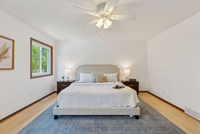 bedroom featuring light wood finished floors, a ceiling fan, and baseboards