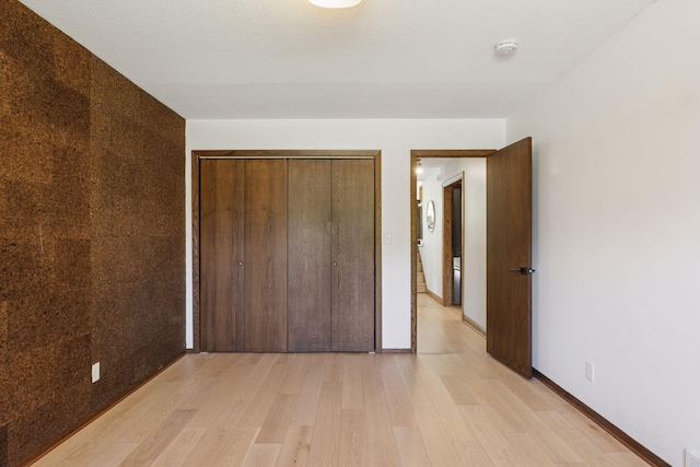 unfurnished bedroom with light wood finished floors, a closet, and baseboards