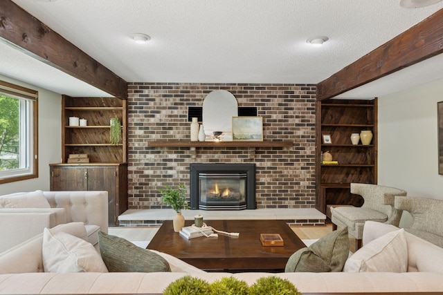living area with a textured ceiling, a fireplace, built in shelves, beam ceiling, and wood finished floors