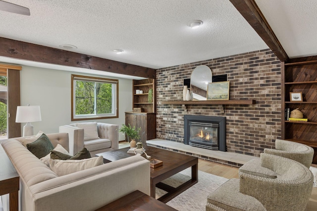 living area with a textured ceiling, wood finished floors, a brick fireplace, plenty of natural light, and built in shelves