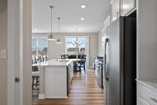19000 72nd Pl N, Maple Grove, MN 55311 - kitchen with stainless steel appliances, a sink, light wood-style flooring, a chandelier, and light countertops
