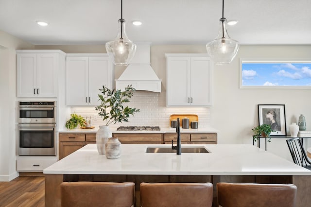 kitchen featuring premium range hood, a sink, stainless steel appliances, backsplash, and recessed lighting