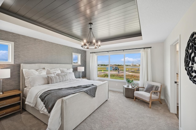 bedroom featuring baseboards, light colored carpet, a chandelier, and a raised ceiling