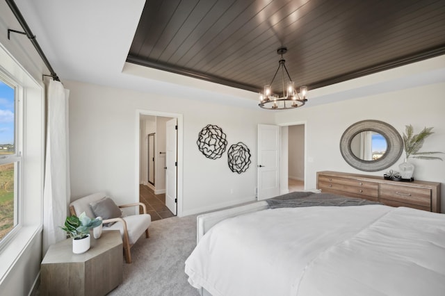 bedroom with a raised ceiling, a chandelier, carpet floors, and baseboards