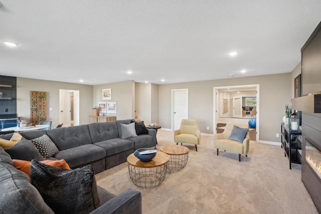 living area with recessed lighting, light carpet, baseboards, and a glass covered fireplace