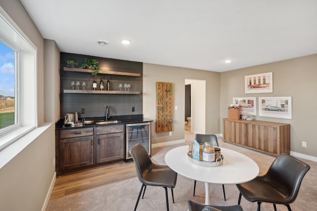 dining area featuring wine cooler, bar with sink, baseboards, recessed lighting, and light wood-type flooring