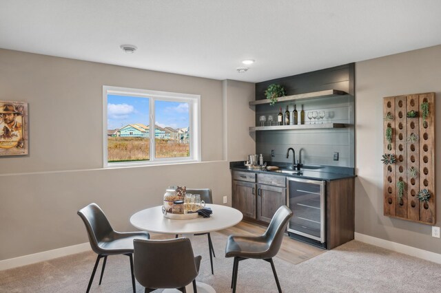 dining area featuring beverage cooler, wet bar, light carpet, and baseboards