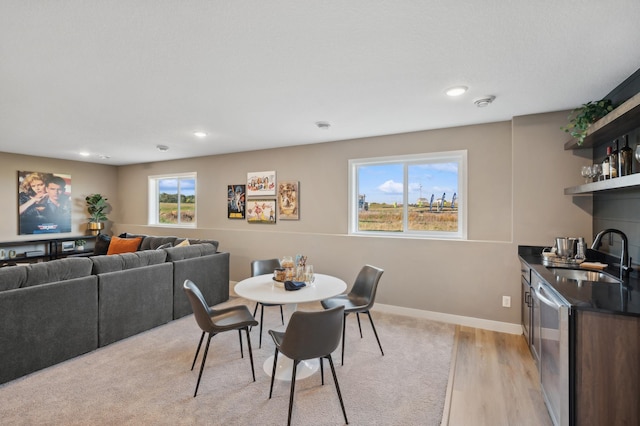 dining space with bar area, recessed lighting, light wood finished floors, and baseboards