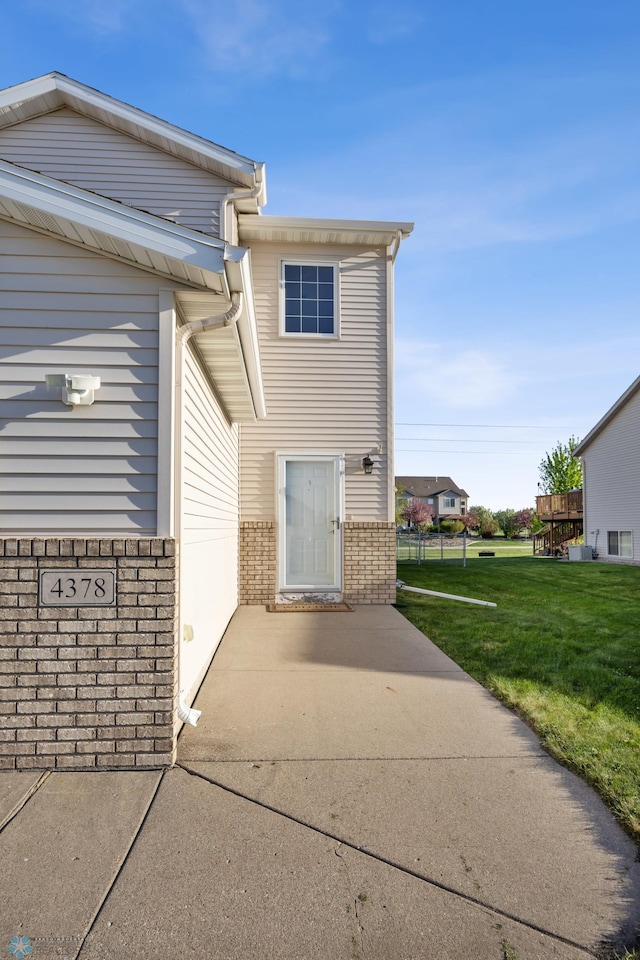 property entrance featuring brick siding and a yard