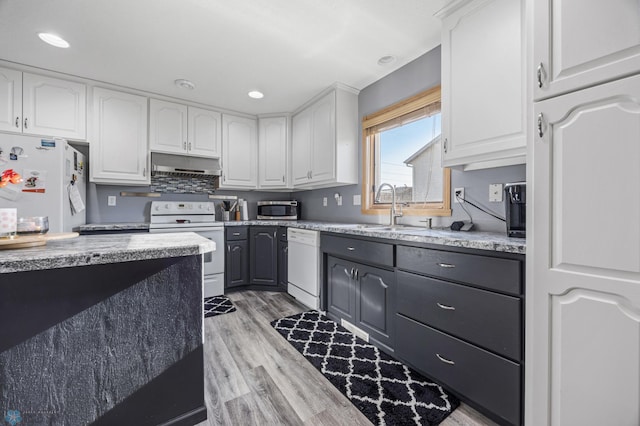 kitchen with white appliances, a sink, white cabinetry, and recessed lighting