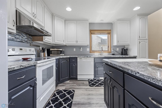 kitchen featuring white appliances, under cabinet range hood, white cabinets, light wood-type flooring, and recessed lighting