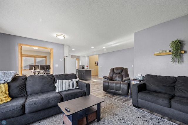 living area featuring light wood-style flooring, recessed lighting, and a textured ceiling