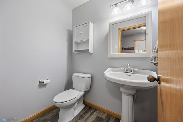 half bath with wood finished floors, toilet, and baseboards