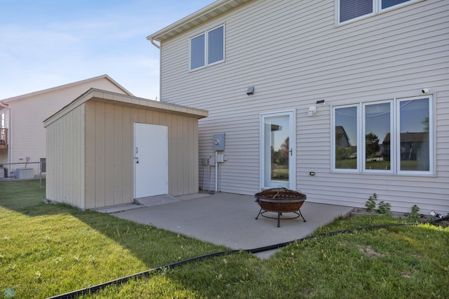 back of house with a patio area, a yard, a fire pit, an outbuilding, and a shed