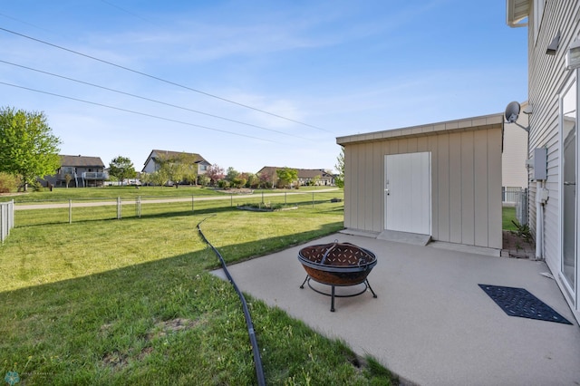 view of yard with an outdoor fire pit, a patio, an outdoor structure, a shed, and a residential view