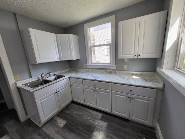 kitchen featuring a sink, dark wood-type flooring, a textured ceiling, and white cabinetry