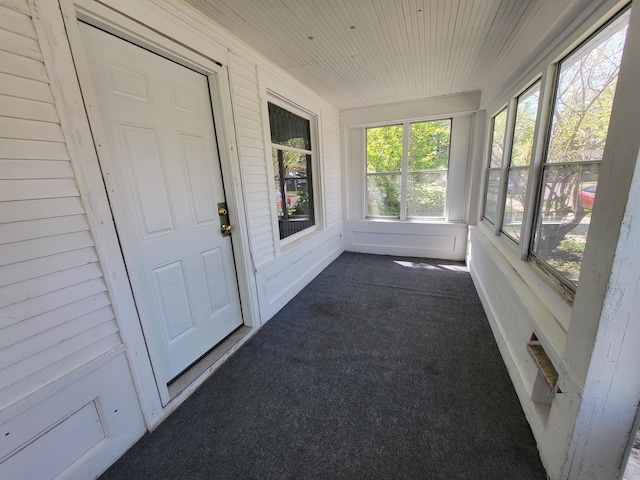 unfurnished sunroom featuring carpet, wooden ceiling, and healthy amount of natural light