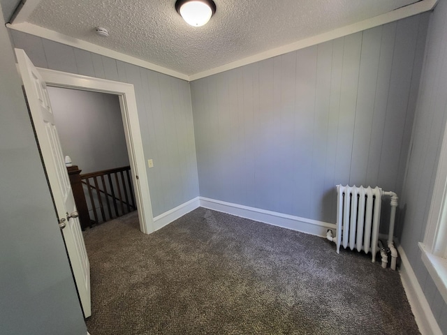 unfurnished room featuring radiator, dark colored carpet, a textured ceiling, and a smoke detector