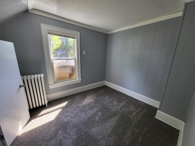 bonus room with radiator, dark carpet, and a textured ceiling