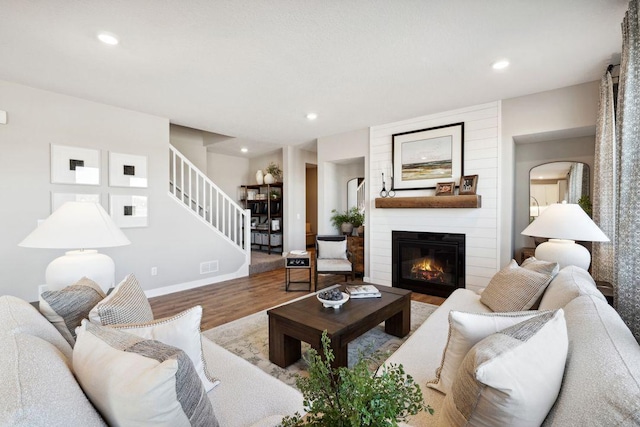 living area featuring stairway, wood finished floors, a fireplace, recessed lighting, and baseboards