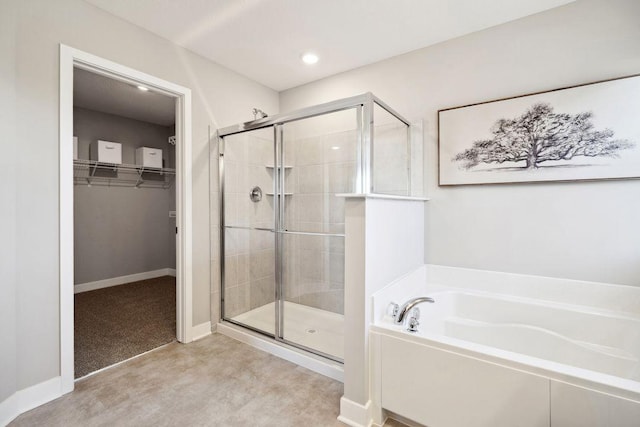 full bath with a stall shower, a walk in closet, a bath, baseboards, and recessed lighting