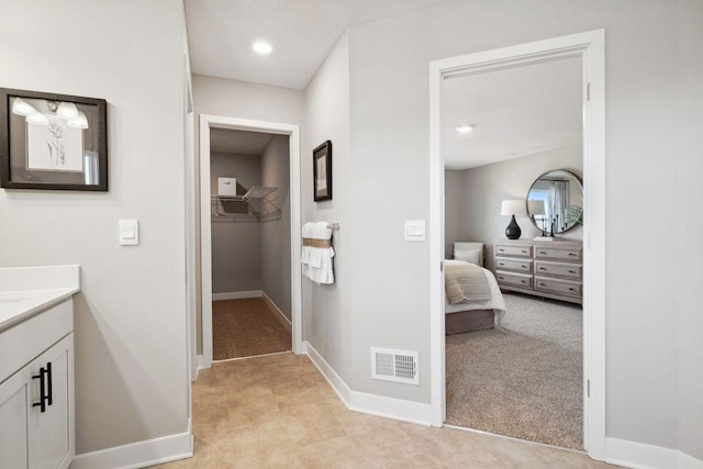 ensuite bathroom with baseboards, vanity, and a walk in closet