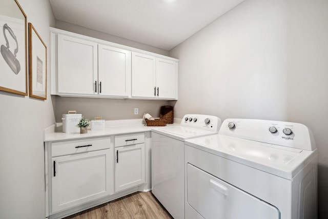 washroom with washing machine and dryer, cabinet space, and light wood-style flooring