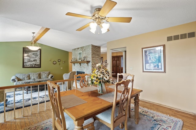 32355 Nottingham Ct, Chisago Lake Twp, MN 55045 - dining room featuring a fireplace, wood finished floors, a ceiling fan, and lofted ceiling