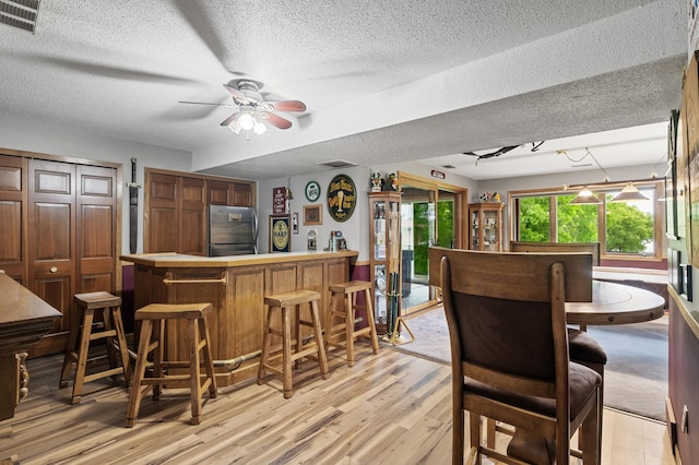 32355 Nottingham Ct, Chisago Lake Twp, MN 55045 - dining room featuring a dry bar, light wood-style flooring, a ceiling fan, and a textured ceiling