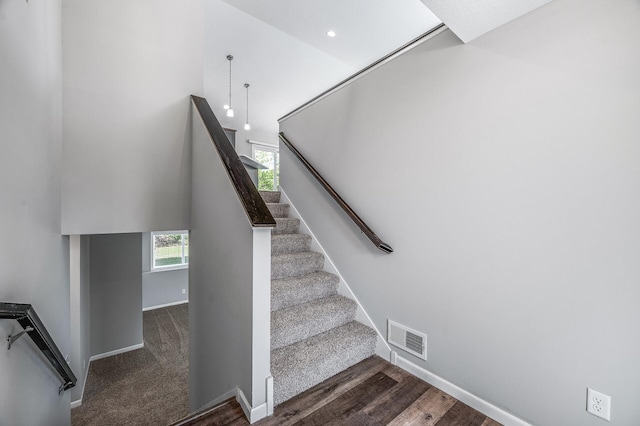 staircase with baseboards, wood finished floors, and a high ceiling