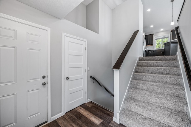 staircase featuring wood finished floors, baseboards, and recessed lighting