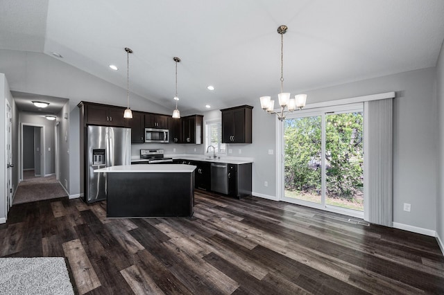 kitchen featuring appliances with stainless steel finishes, light countertops, vaulted ceiling, a center island, and dark wood-type flooring