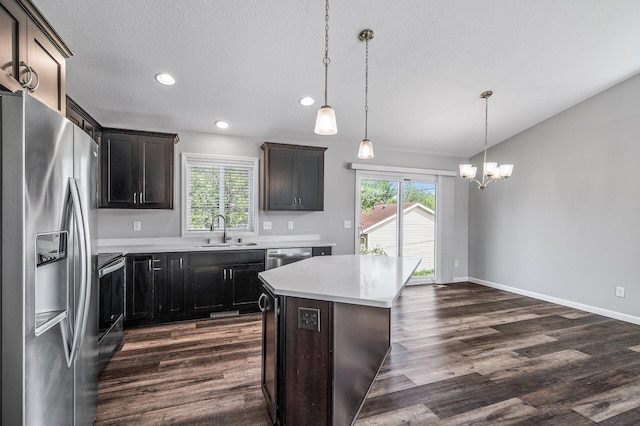 kitchen featuring appliances with stainless steel finishes, a sink, dark wood finished floors, a chandelier, and light countertops