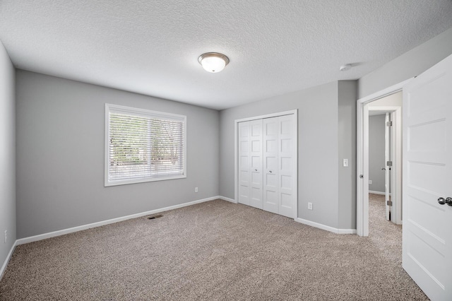 unfurnished bedroom featuring carpet floors, a closet, a textured ceiling, and baseboards