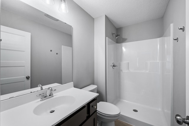 bathroom featuring a textured ceiling, a shower, toilet, and vanity