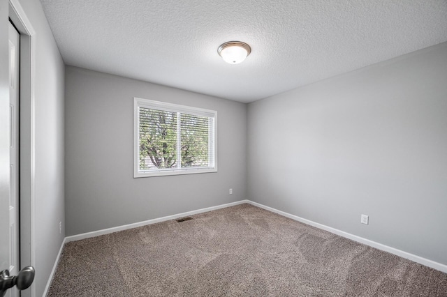 spare room featuring carpet, a textured ceiling, and baseboards