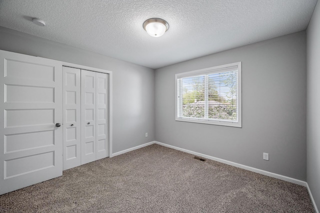 unfurnished bedroom featuring carpet flooring, a textured ceiling, a closet, and baseboards
