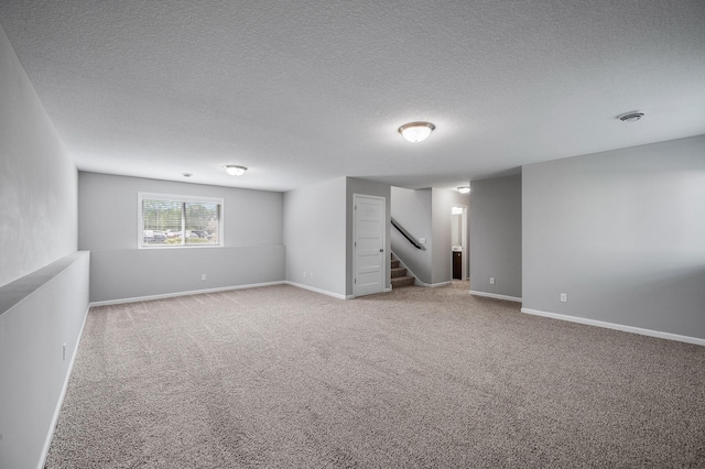 below grade area featuring carpet, stairs, a textured ceiling, and baseboards