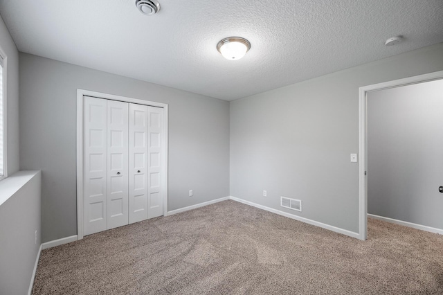 unfurnished bedroom with a closet, carpet, baseboards, and a textured ceiling